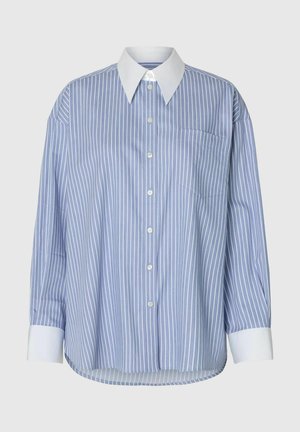 Sinivalkoraidallinen nappipaita, jossa on klassinen kaulus ja pitkät hihat. Siinä on yksi rintatasku ja kaareva helma.