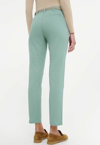 Jasnozielone, dopasowane spodnie o prostym kroju, zestawione z plecionym pasek oraz brązowymi butami wsuwanymi, prezentujące gładką teksturę.