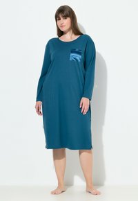 Vestido de noche de manga larga en color verde azulado, hecho de un tejido suave, con un bolsillo de satén, corte relajado y aberturas laterales para facilitar el movimiento.