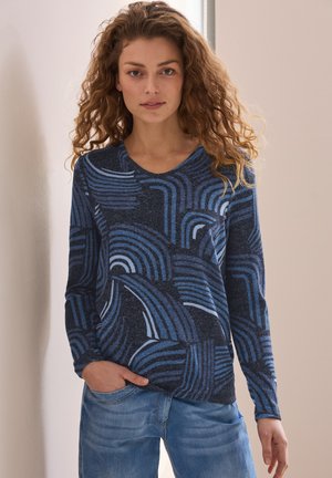 Maglietta a maniche lunghe caratterizzata da una base blu scuro con motivi geometrici a onde blu chiaro. Texture morbida con scollatura rotonda e vestibilità rilassata.