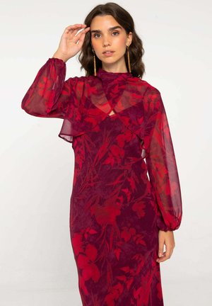 Vestido rojo con flores que presenta mangas transparentes, un cuello alto y una silueta ajustada. La tela tiene una textura suave, con un intrincado patrón floral.