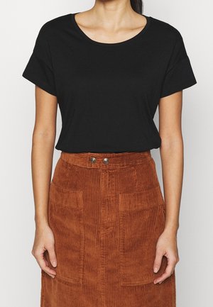 Sort T-shirt med korte ærmer og rund halsudskæring, kombineret med en rustrød manchesternederdel med forlommer og knapdetaljer.