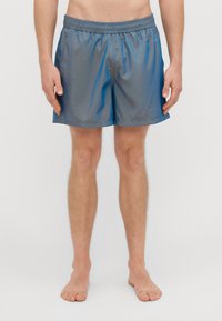 Grå badeshorts laget av lett materiale med elastisk midjebånd. Har en glatt tekstur og et enkelt, klassisk design.