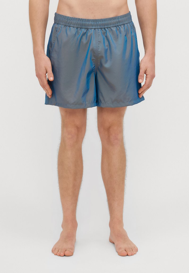 Grå badeshorts laget av lett materiale med elastisk midjebånd. Har en glatt tekstur og et enkelt, klassisk design.
