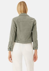 Chaqueta de mezclilla verde con un diseño ajustado, costuras estructuradas y detalles de botones en los puños, de longitud corta y con dos bolsillos traseros.