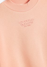 Felpa rosa con colletto a coste. Presenta la scritta ricamata "LOS ANGELES City of Wonderful Est. 1996" in filo rosa abbinato.