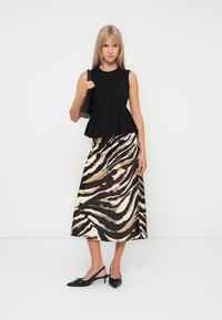 Black sleeveless peplum top paired with a long, flowing skirt featuring a zebra print in shades of black, beige, and brown. Black slingback shoes.