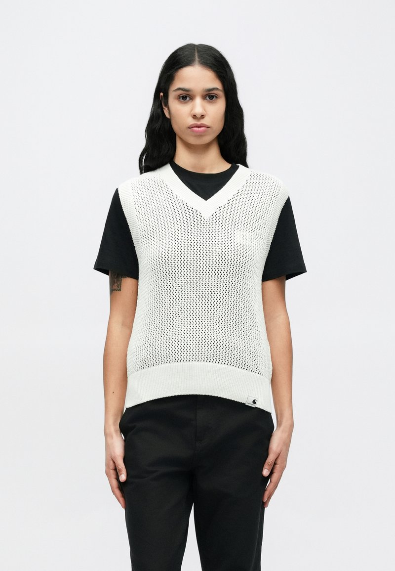 Gilet lavorato a maglia leggero color crema con scollo a V, caratterizzato da una texture a rete e orlo a coste, indossato sopra una T-shirt nera a maniche corte.