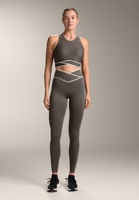 Sports bra and high-waisted leggings in dark gray with white accent stripes. The material is smooth and fitted, designed for activewear.