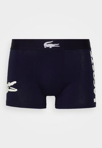 Boxers de marinero hechos de una tela suave, con un logo de cocodrilo blanco en la pierna izquierda y "LACOSTE" impreso en blanco en la cintura.