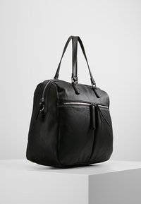 Černá kožená taška typu tote s texturovaným povrchem, dvěma uchy, dvěma předními kapsami na zip a prostornou hlavní přihrádkou.