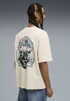 Cream cotton t-shirt featuring a black and green graphic of a roaring panther, with a stylized border and the word "PUMA" above.