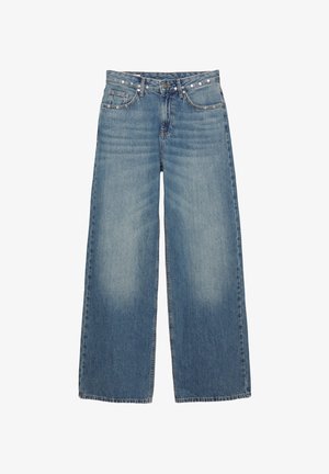 Široke modre kavbojke z izpostavljenim denim koncem. Imajo pet žepov, gumb zapiranje in dekorativno opremo vzdolž pasu.