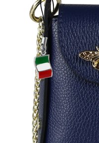 Marineblauwe leren handtas met een gouden kettinghengsel en een zilveren bevestiging met een kleine Italiaanse vlag. Vlinderaccent aan de voorkant.