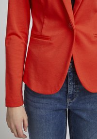 Rode blazer met een gladde textuur, enkele knoopsluiting en twee zijzakken, gecombineerd met blauwe denim jeans. Op maat gemaakte pasvorm, gestructureerd ontwerp.