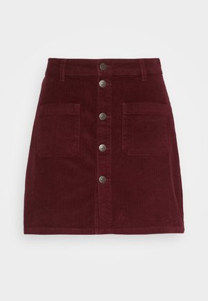 Jupe en velours côtelé bordeaux avec une fermeture à boutons, deux poches plaquées et une silhouette droite. Présente un tissu texturé et des boutons en métal argenté.