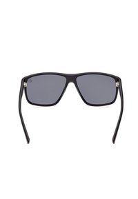 Gafas de sol rectangulares negras con lentes tintados en gris, marco de plástico mate, acentos de metal en los laterales y patillas delgadas negras.