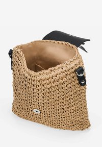 Bolsa de paja tejida con un interior en tono marrón. Cierre de solapa negro y correas de hombro con herrajes plateados. Diseño de apertura en la parte superior, forma estructurada.