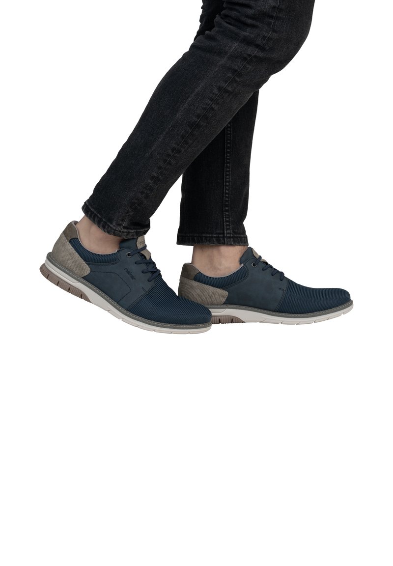 Baskets bleuies avec une tige texturée et des accents gris. Les caractéristiques incluent une semelle rembourrée et un design à lacets. Ensemble porté avec un jean foncé.