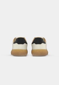 White sneakers with a textured brown sole, featuring a black heel accent and smooth upper material. Two shoes shown from the back view.