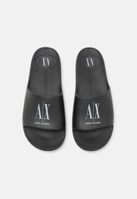 Sorte gummistøvler med flade såler. Har en rund åben tå og præget hvide logoer: "A|X" og "ARMANI EXCHANGE." Glat overflade.