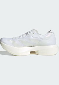 Chaussure de sport blanche avec une tige en maille texturée, des accents lisses contrastants, une semelle à coussinage épais et un système de laçage. Présente un détail de logo.