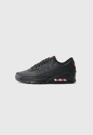 Nike Air Max 90 lenkkarit, joissa on musta synteettinen päällinen, väriteräksinen pinta, nauhakiinnitys, näkyvä ilmasäiliö ja oranssi logoväri.