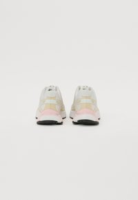 Hvite og beige joggesko med rosa detaljer, teksturert overmateriale, polstret krage og en slitesterk svart såle.