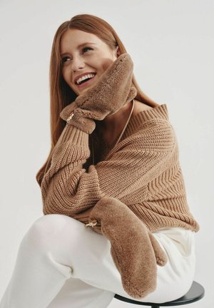 Brązowy sweter dziany o prążkowanej fakturze, w połączeniu z miękkimi, pluszowymi brązowymi rękawiczkami. Rękawiczki mają zaokrąglony kształt i zamek jako akcent.