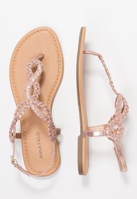 Ruusu kullanasta litteät sandaalit, joissa on punottu muotoilu remmeissä ja sileä beige pohja. Varustettu turvallisella nilkkaremmillä ja minimalistisella varusteella.