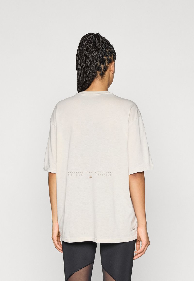 Φαρδιά oversized μπλούζα σε ανοιχτό μπεζ χρώμα με κοντά μανίκια. Διαθέτει εκτυπωμένο κείμενο κοντά στο κάτω μέρος και στρογγυλή λαιμόκοψη. Απαλή υφή υφάσματος.