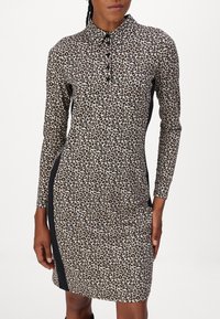 Leopardenmusterkleid mit Kragen, langen Ärmeln und seitlichen Einsätzen in kontrastierendem Schwarz, gefertigt aus einem glatten, dehnbaren Stoff.