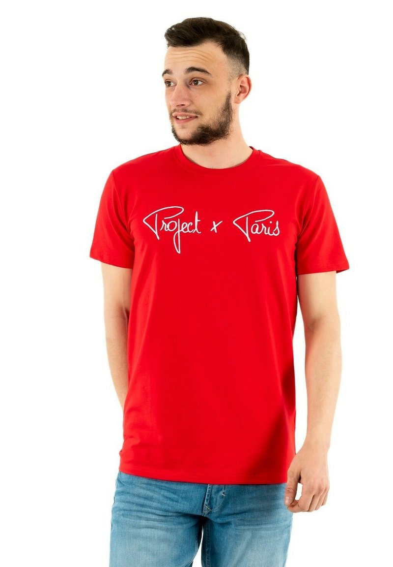 Red cotton t-shirt featuring white script text "Project x Paris." Classic crew neck design with short sleeves and a regular fit.