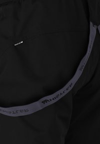 Svart tyg med en liten svart och vit Whistler-märkesetikett och ett mörkgrått band tryckt med Whistler-logotypen och text.