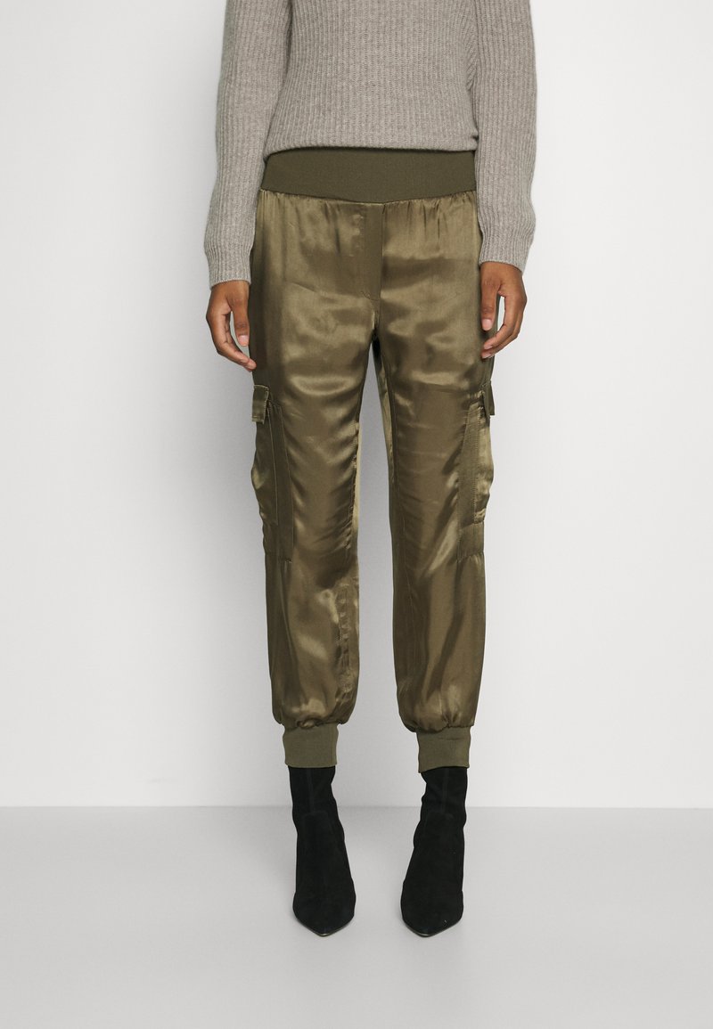 Olive green satin cargo pants with ribbed waistband and ankle cuffs, featuring side pockets and a smooth texture, paired with black boots.