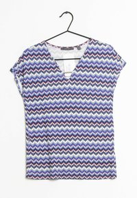 Maglietta a maniche corte con scollo a V in morbido tessuto, caratterizzata da un motivo a zigzag nei colori blu, bianco e rosso. Presenta un'etichetta visibile all'interno.