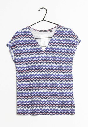 Maglietta a maniche corte con scollo a V in morbido tessuto, caratterizzata da un motivo a zigzag nei colori blu, bianco e rosso. Presenta un'etichetta visibile all'interno.