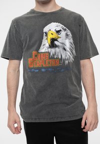 Gray cotton t-shirt featuring a graphic of an eagle's head and "Chris Stapleton" text in red and yellow, with a worn texture.