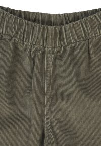 Olijfgroene corduroy stof met een verticale geribbelde textuur, voorzien van een elastische tailleband en gestikte naden voor een ontspannen pasvorm.