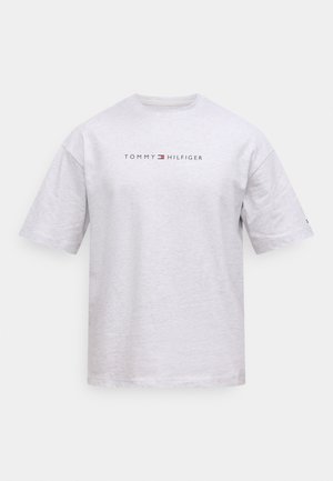 Camiseta de algodón gris con mangas cortas, que presenta un logo impreso "TOMMY HILFIGER" en negro y rojo en el pecho. Cuello redondo clásico.