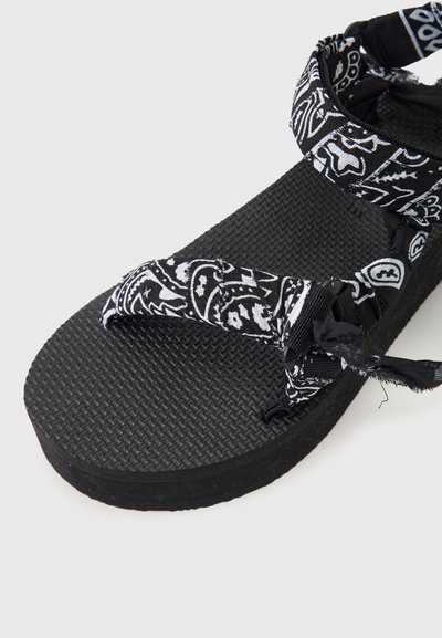 Μαύρο σανδάλι με υφή στη σόλα και λουριά από ύφασμα με ασπρόμαυρο μοτίβο, που διαθέτει ρυθμιζόμενους κρίκους και σχεδιασμό με δάχτυλο.