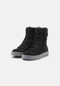 Botas altas negras de ante con un collar de piel texturizada, cordones en la parte delantera y una suela de goma gris. Presentan sutiles acentos de brillo.