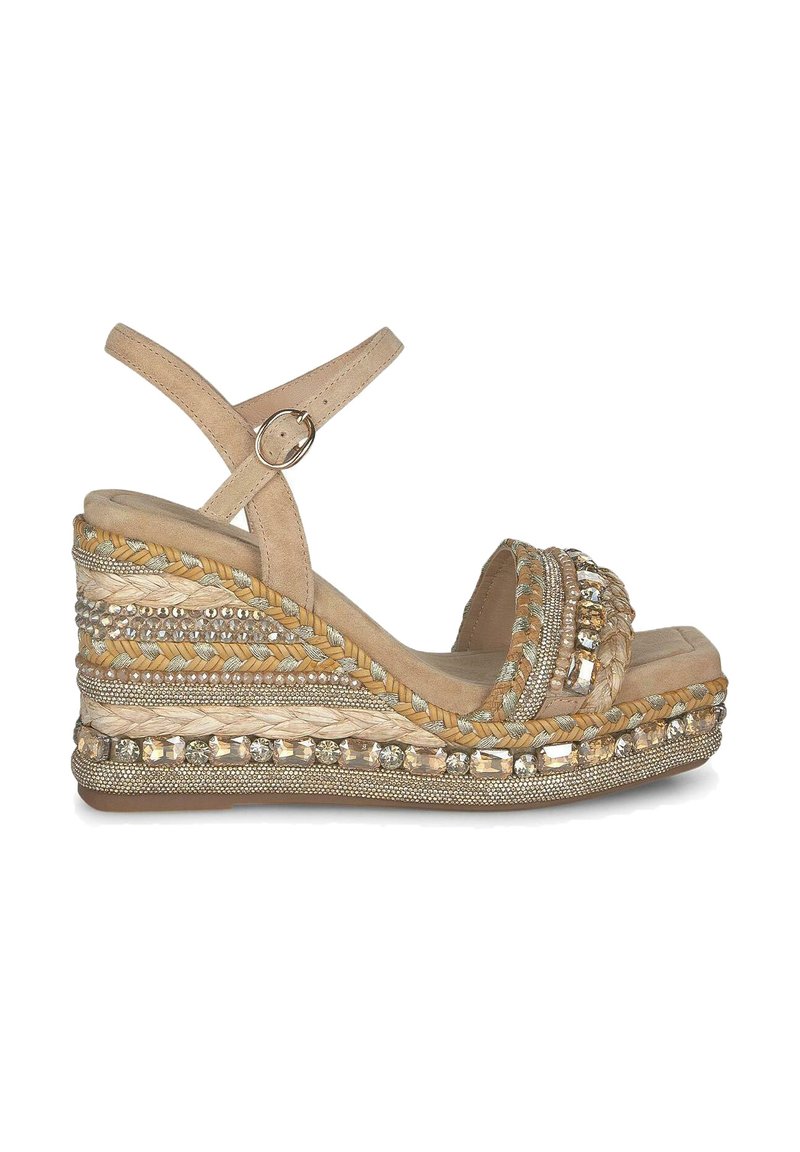 Sandale compensée beige avec un design en jute tressé et des accents décoratifs en cristal. Elle présente une large sangle et une boucle à la cheville pour un maintien sécurisé.