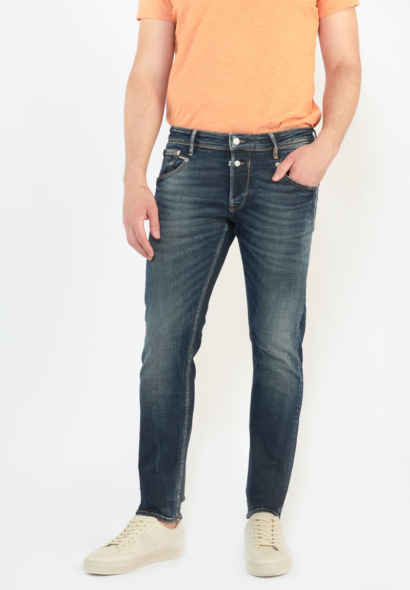 Jeans ajustados de hombre en denim azul oscuro con un ligero desgaste, diseño de cinco bolsillos, cierre con botones y detalles de costura en contraste.