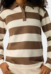 Camisa polo de manga larga a rayas marrón y crema con cuello, tapeta de tres botones y tejido texturizado, ajustada a la cintura.