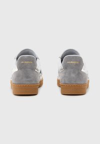 Sneakers in suede grigio e pelle bianca caratterizzati da un design testurizzato, tallone grigio chiaro e suola in gomma marrone con dettagli del logo in oro.