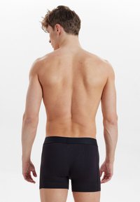 Svarta boxershorts i mjukt tyg, med elastisk midja och en figurnära design. Texturerad yta utan synliga mönster eller logotyper.