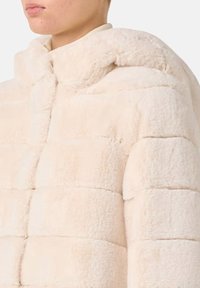 Faux fur pufferjack in zacht beige, met een geometrisch patroon waarin opvallende horizontale strepen zijn verwerkt en een capuchon. Soepele textuur.