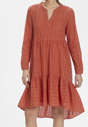 Korallorange klänning med långa ärmar, v-ringning, lager-på-lager volangkant och hålbroderade detaljer genom hela plagget. Tillverkad av lättviktsmaterial.
