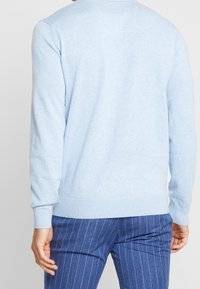 Light blue sweater with long sleeves and ribbed cuffs, made from soft fabric. Features a simple design with a crew neck and no visible patterns.